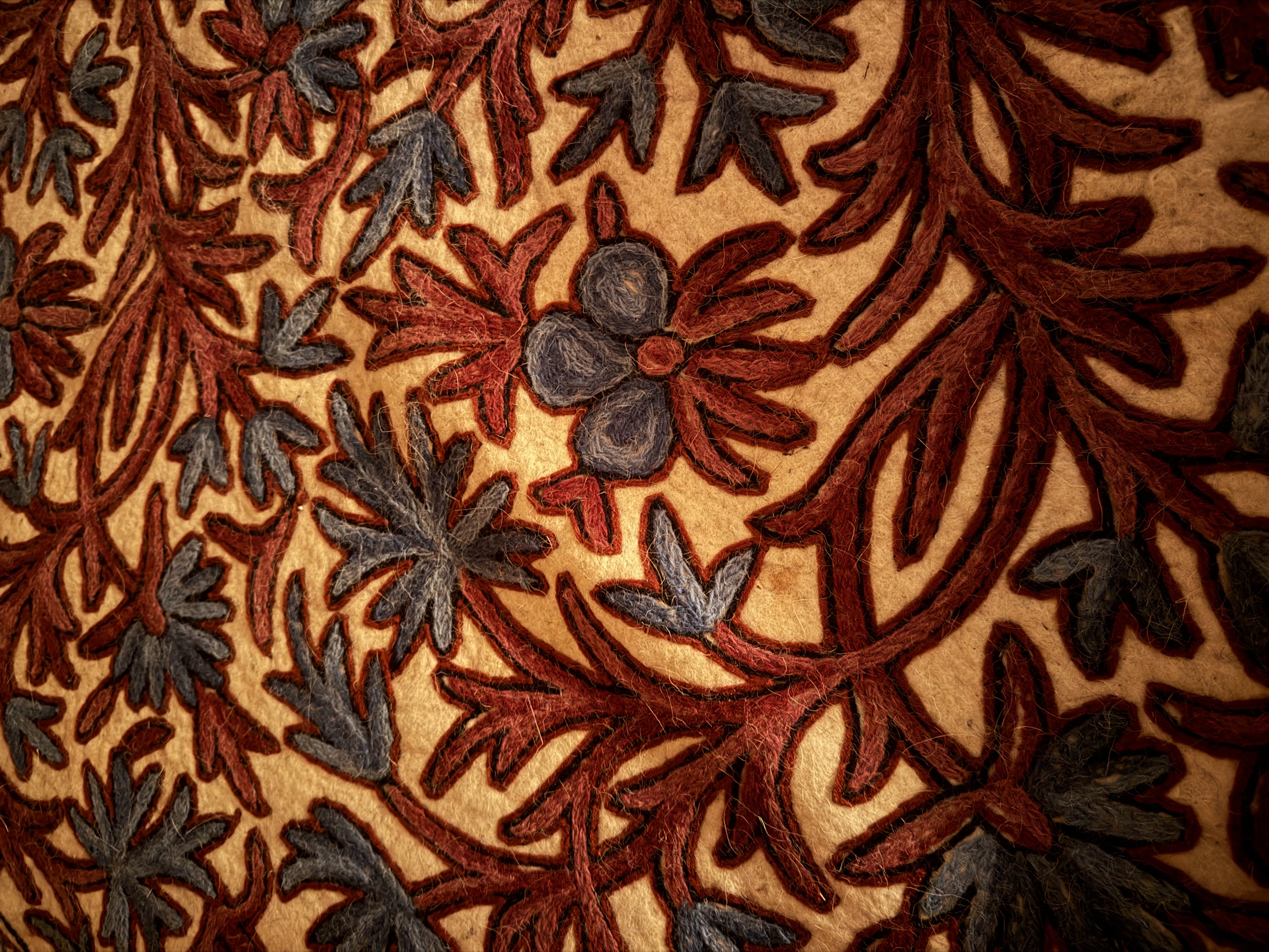 Hand-embroidered crewelwork textile in rust and slate wool on a warm felt ground, from the sanctuary floor